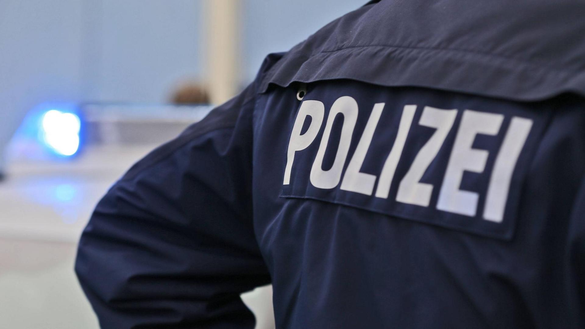 Polizei-Schriftzug auf dem Rücken eines Polizisten Polizei-Schriftzug auf dem Rücken eines Polizisten