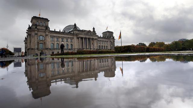 Der Reichstag spiegelt sich in einer Regenpfütze.