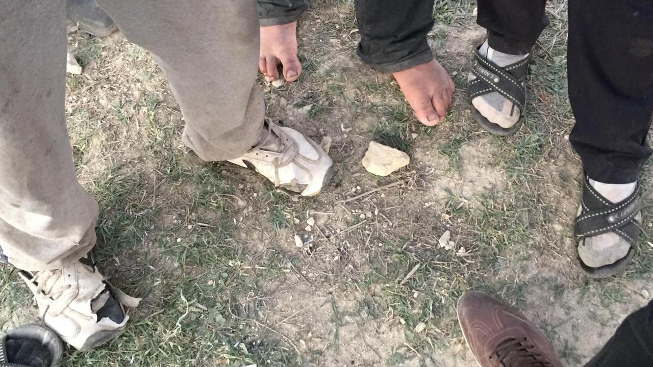 Blick auf die Füße von mehreren Männern mit zerschlissenen Schuhen oder barfuß Blick auf die Füße von mehreren Männern mit zerschlissenen Schuhen oder barfuß