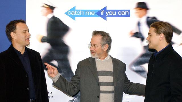 Die US-Schauspieler Leonardo DiCaprio (r.) und Tom Hanks (l.) sowie der Regisseur Steven Spielberg stehen am 26.1.2003 in Berlin vor einem Kinoplakat zu ihrem Streifen "Catch Me If You Can".