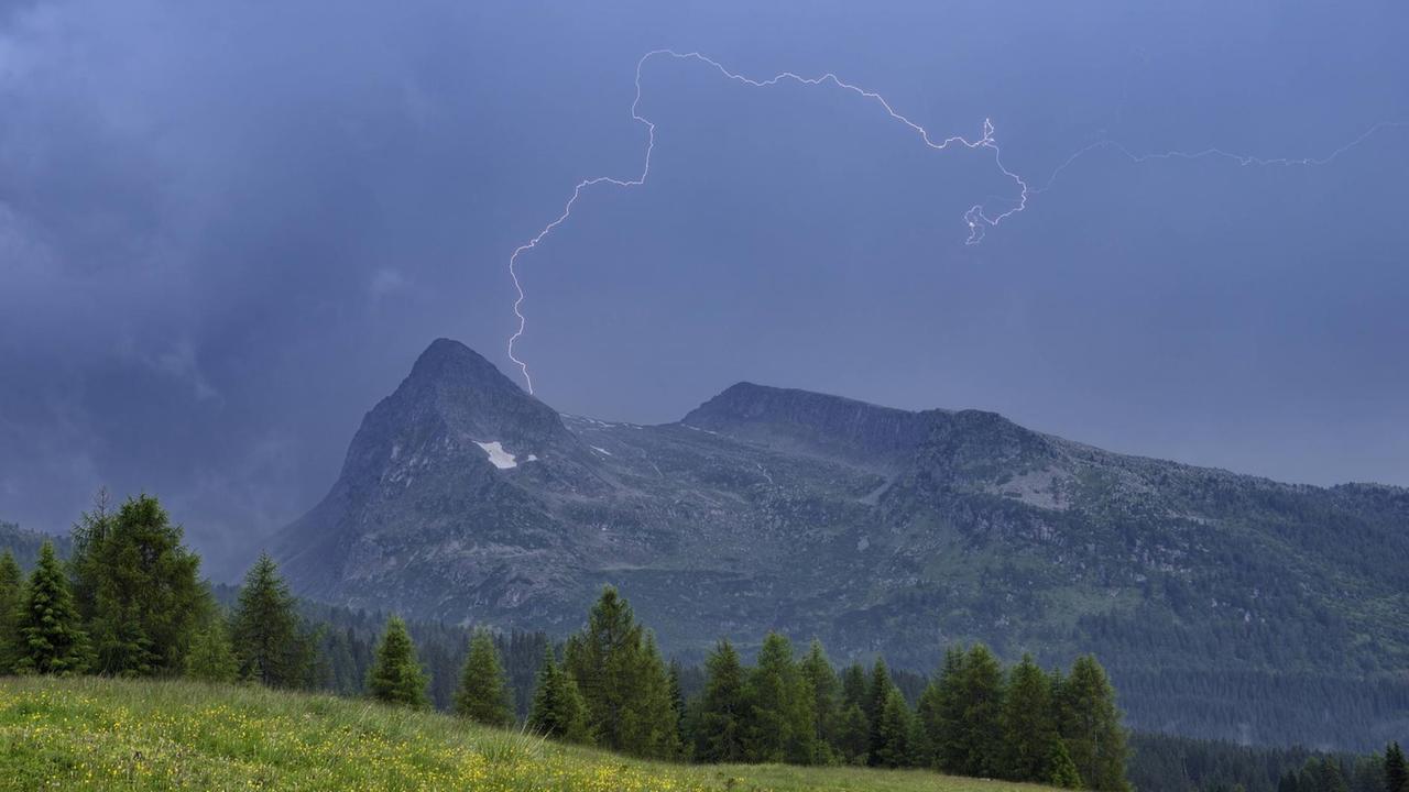 Ein Blitz ist über einem Bergmassiv in den Dolomiten zu sehen. Ein Blitz ist über einem Bergmassiv in den Dolomiten zu sehen.