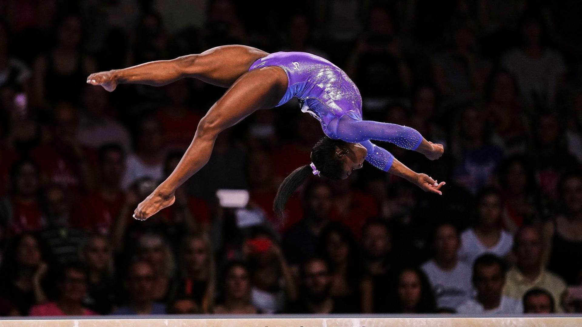 Simone Biles bei einem Sprung auf dem Schwebe-Balken Simone Biles bei einem Sprung auf dem Schwebe-Balken
