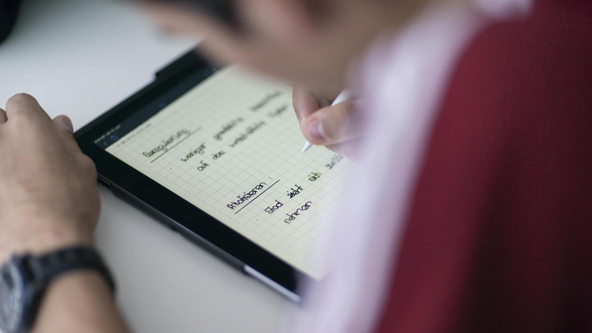 Ein Schüler, gebeugt über ein Tablet Ein Schüler, gebeugt über ein Tablet