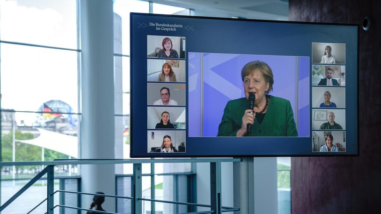 Bundeskanzlerin Angela Merkel ist bei der digitalen Dialogreihe "Die Bundeskanzlerin im Gespräch" mit ehrenamtlichen Helfern auf einem Bildschirm im Bundeskanzleramt zu sehen. Bundeskanzlerin Angela Merkel ist bei der digitalen Dialogreihe "Die Bundeskanzlerin im Gespräch" mit ehrenamtlichen Helfern auf einem Bildschirm im Bundeskanzleramt zu sehen.