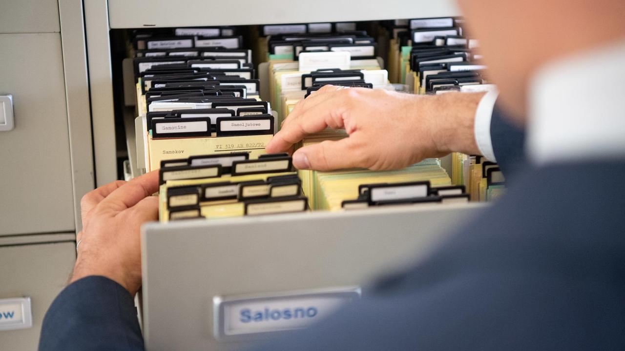 Blick auf eine Schublade mit Karteikarten, die von einem Mann geöffnet wird. Blick auf eine Schublade mit Karteikarten, die von einem Mann geöffnet wird.