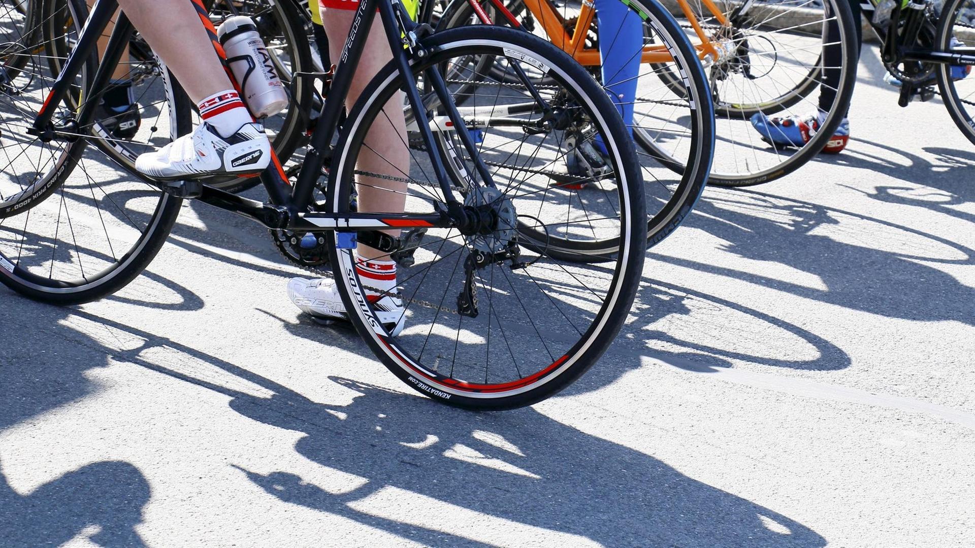 Bei einem Radsport-Straßenrennen stehen mehrere Fahrer mit ihren Rädern nebeneinander. Bei einem Radsport-Straßenrennen stehen mehrere Fahrer mit ihren Rädern nebeneinander.