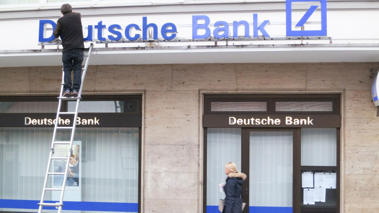 An einer Filiale der Deutschen Bank in München repariert ein Arbeiter den Schriftzug. 