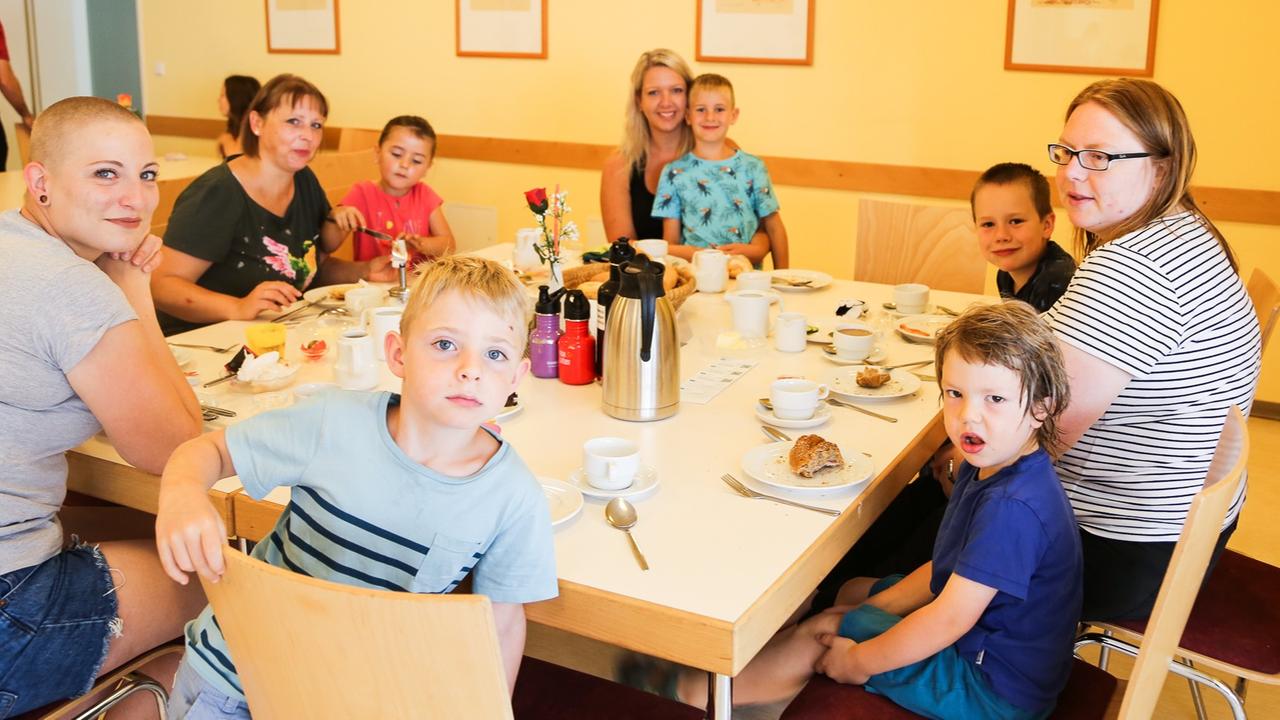 An einem Tisch sitzen Mütter mit ihren Kindern beim Essen. An einem Tisch sitzen Mütter mit ihren Kindern beim Essen.