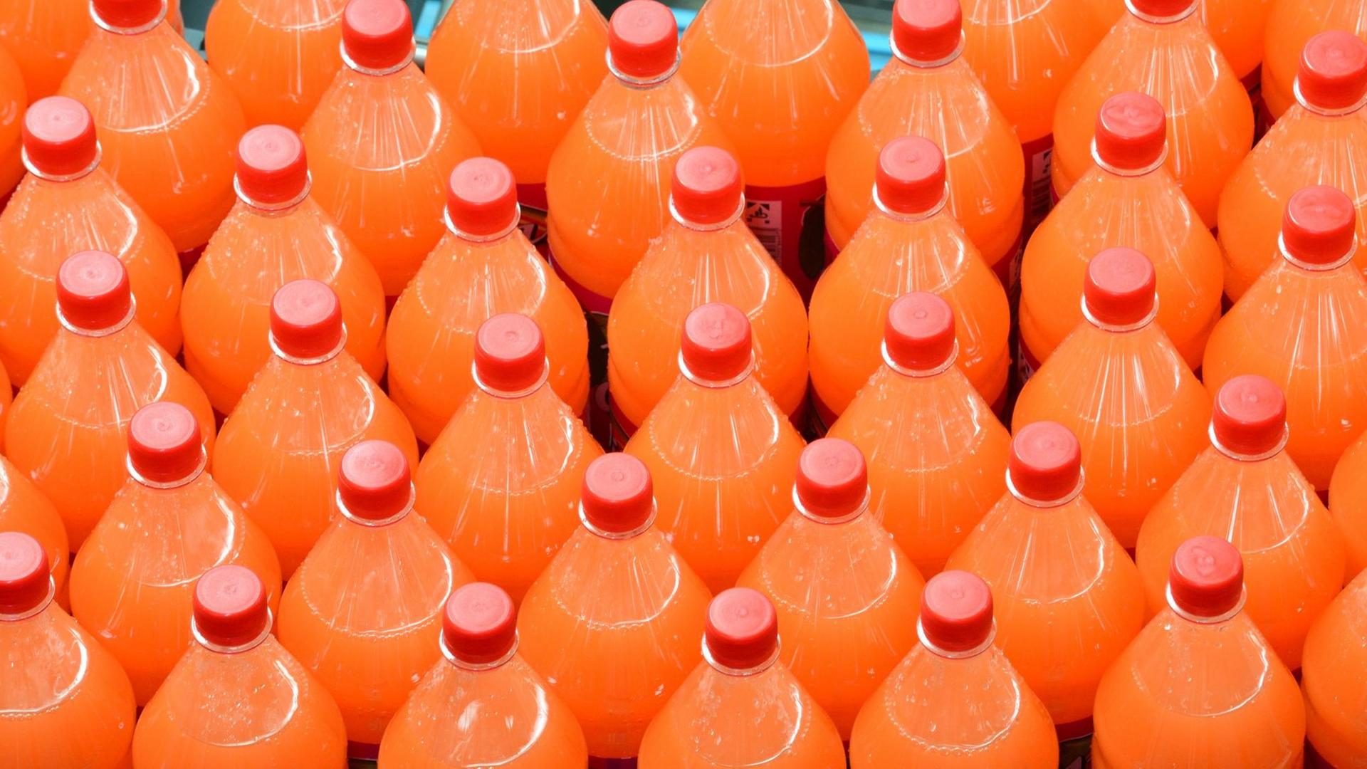 Limonaden-Flaschen werden auf einem Produktionsband weitertransportiert. Limonaden-Flaschen werden auf einem Produktionsband weitertransportiert.