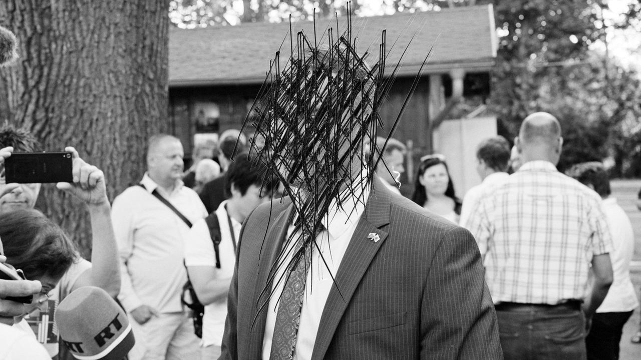 Auf einem Schwarzweiß-Foto ist das Gesicht der zentral abgebildeten Person bis zur Unkenntlichkeit zerkratzt. Es handelt sich um den AfD-Kandidaten für die Bürgermeisterwahl 2019 in Görlitz, Sebastian Wippel.