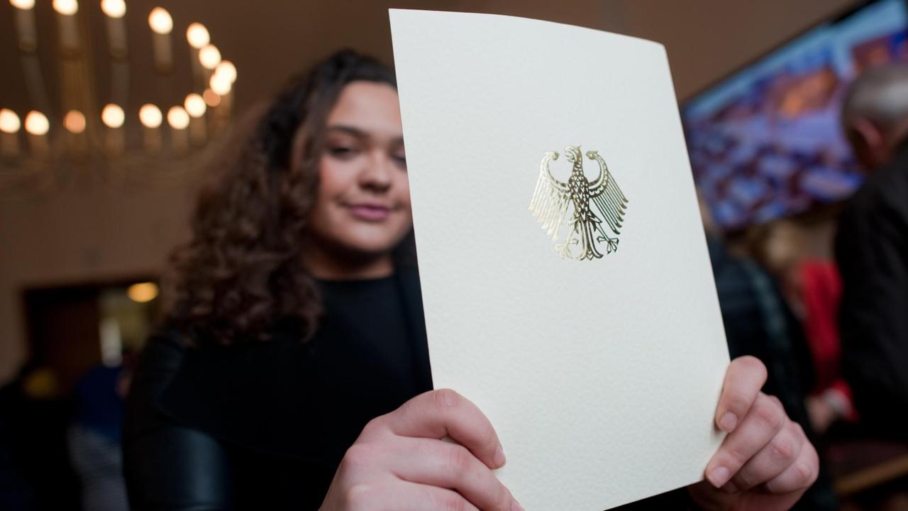 Eine junge Frau zeigt in Berlin im Rathaus Neukölln das Heft mit ihrer Einbürgerungsurkunde. Eine junge Frau zeigt in Berlin im Rathaus Neukölln das Heft mit ihrer Einbürgerungsurkunde.