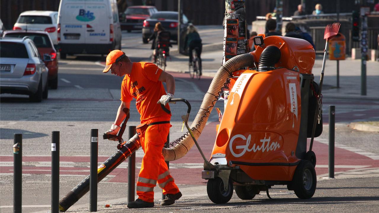Ein Mitarbeiter der Berliner Stadtreinigung BSR benutzt einen Riesensauger, um in Berlin die Straße zu reinigen.