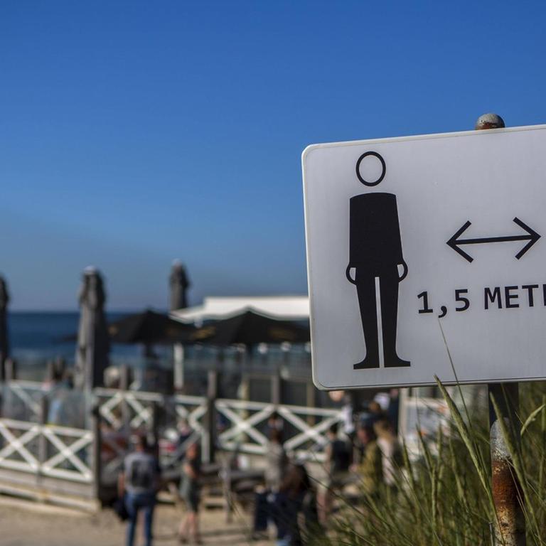 Ein Schild am Strand, das 1,5 Meter Abstand fordert