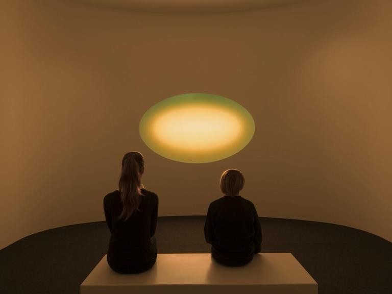 Zwei Ausstellungsbesucher sitzen vor dem Werk "Curved Wide Glass" von James Turrell im Museum Frieder Burda in Baden-Baden
