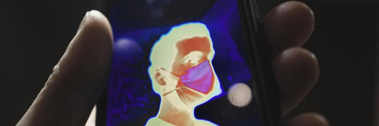 Ein thermisches Selbstporträt mit Maske auf einem Mobiltelefon. Ein thermisches Selbstporträt mit Maske auf einem Mobiltelefon.