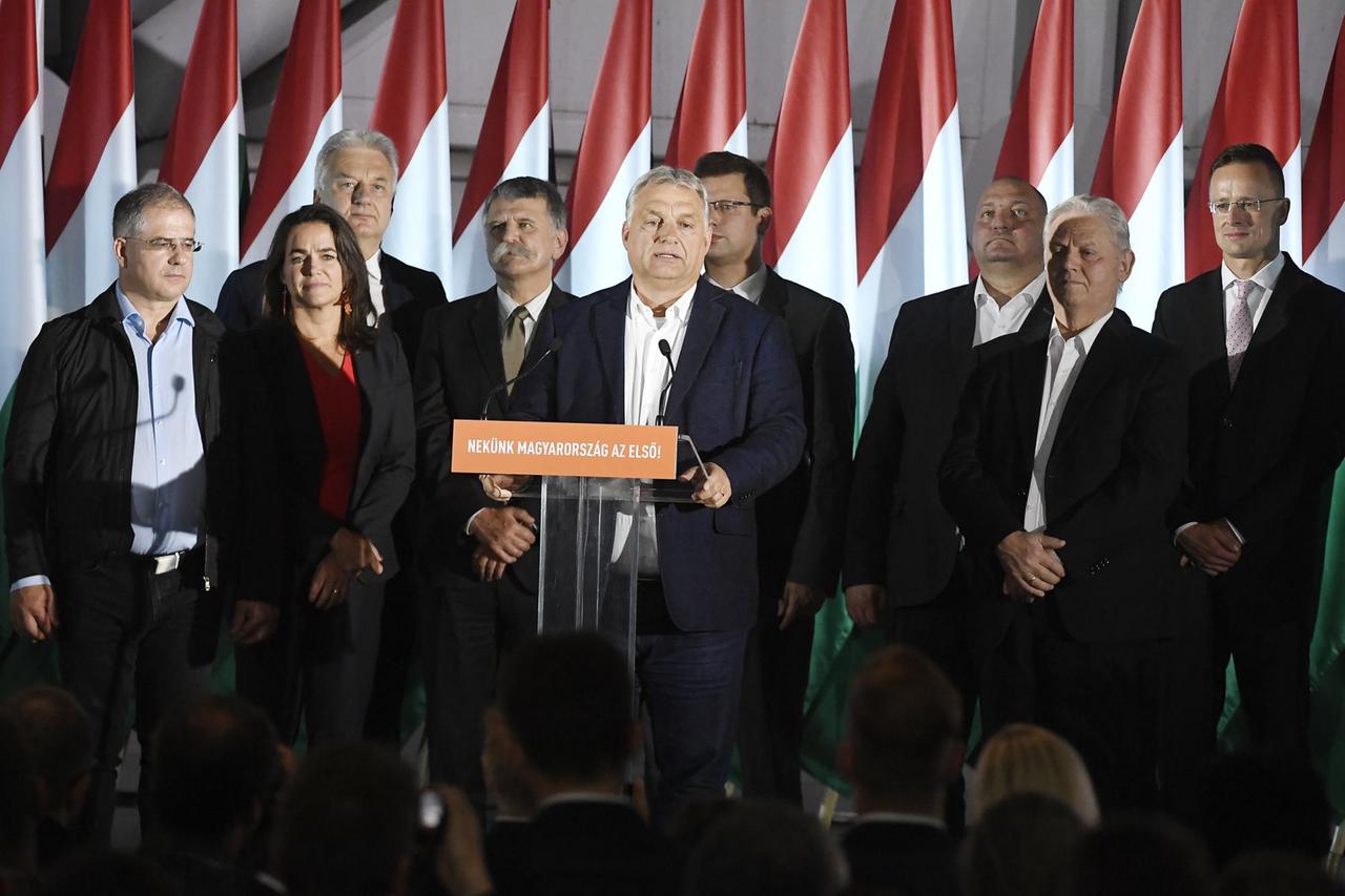 Ornab steht inmitten seiner Parteifreunde an einem Rednerpult und spricht mit ernstem Blick. Im Hintergrund viele ungarische Fahnen.