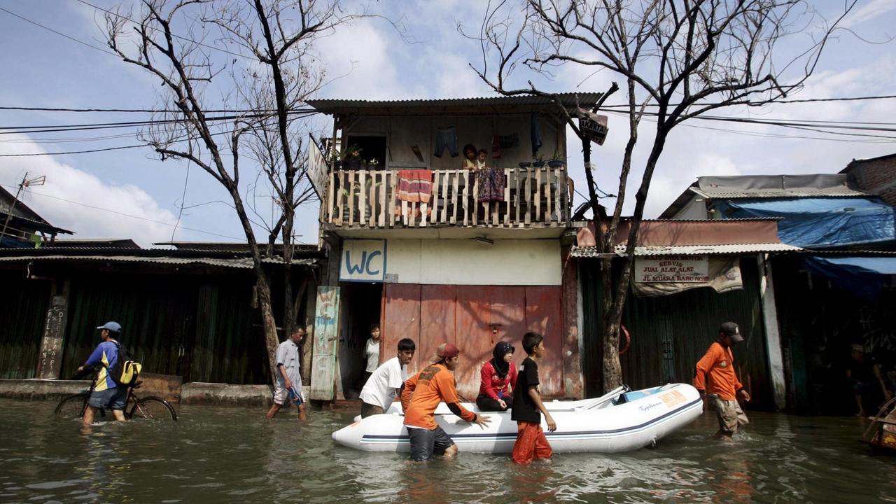 Bewohner der indonesischen Hauptstadt Jakarta waten durch eine überschwemmte Straße. Bewohner der indonesischen Hauptstadt Jakarta waten durch eine überschwemmte Straße.
