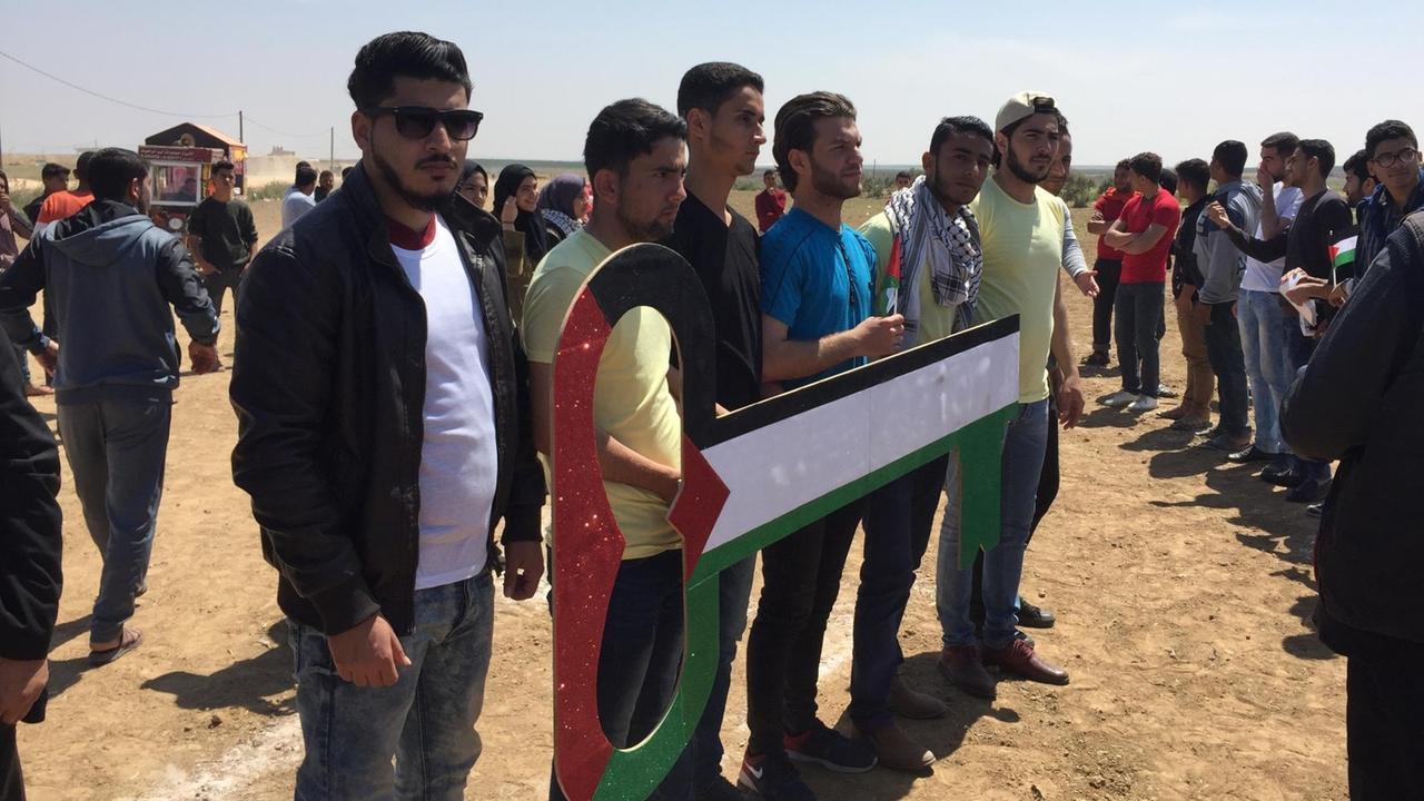 Junge Männer protestieren im Gaza-Streifen und halten einen großen Schlüssel in den Landesfarben in den Händen.