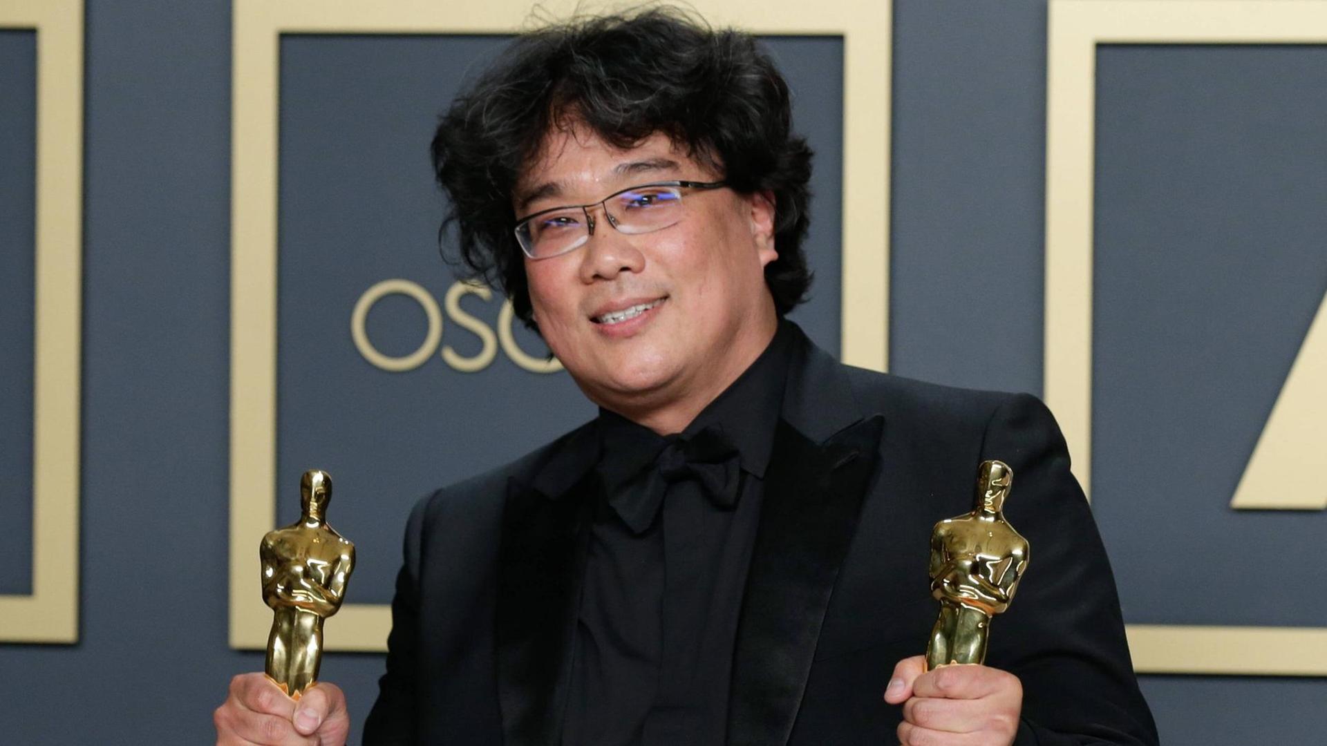 Regisseur Bong Joon-ho hat zwei Oscar-Trophäen in der Hand Regisseur Bong Joon-ho hat zwei Oscar-Trophäen in der Hand
