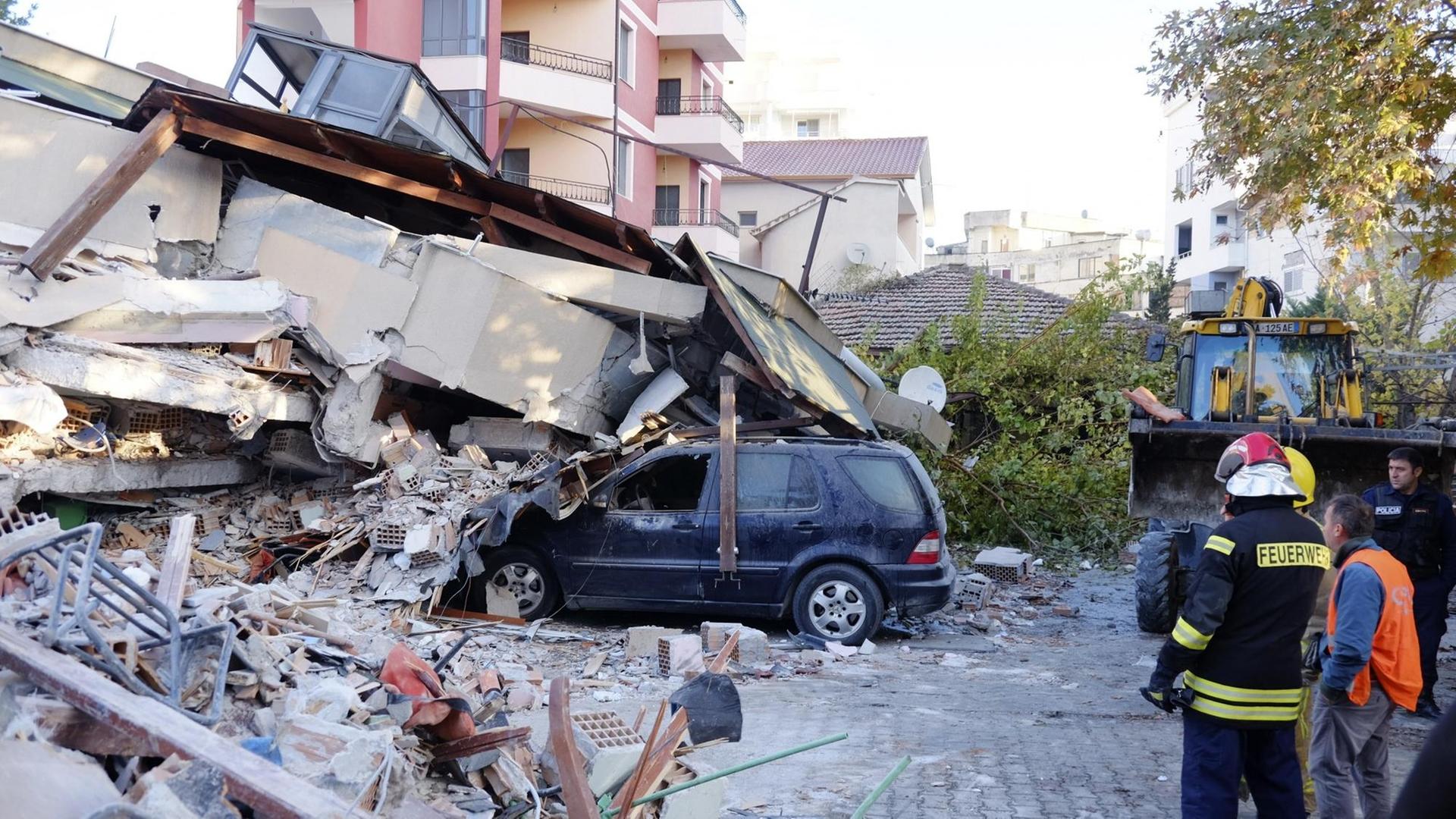 Feuerwehrleute stehen nach einem Erdbeben in Westalbanien neben einem eingestürzten Gebäude, das zum Teil auf ein Auto gestürzt ist. Feuerwehrleute stehen nach einem Erdbeben in Westalbanien neben einem eingestürzten Gebäude, das zum Teil auf ein Auto gestürzt ist.