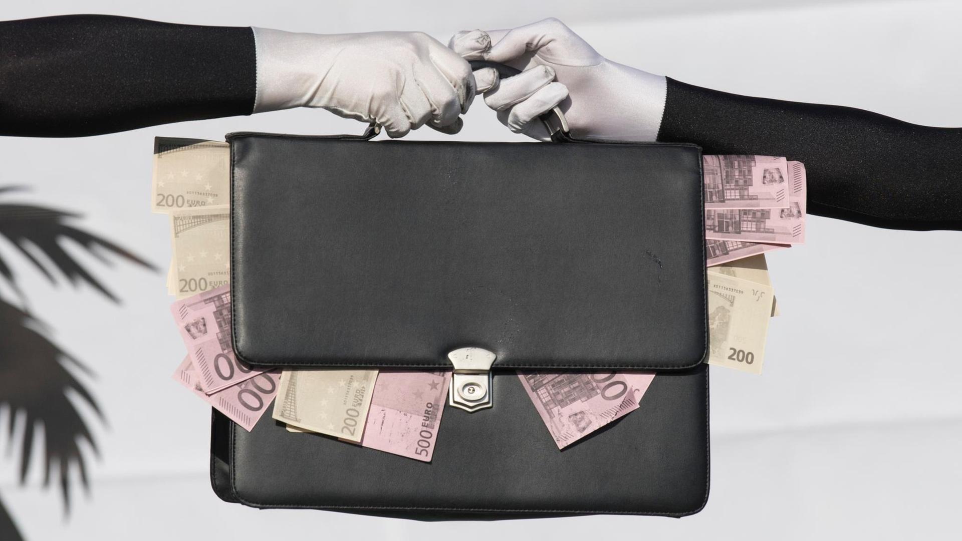 Eine Tasche mit heraushängenden Geldscheinen geht von einer Hand in die andere. Eine Tasche mit heraushängenden Geldscheinen geht von einer Hand in die andere.