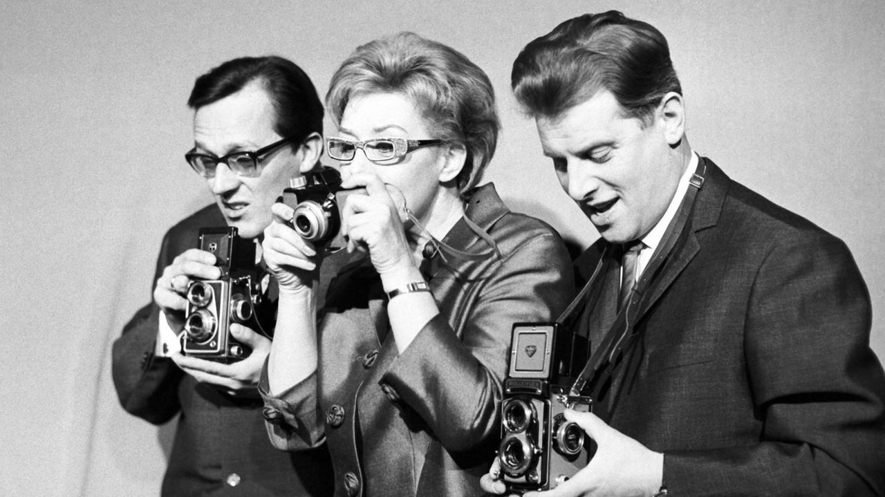 Die Mitglieder des Münchner Kabaretts "Lach- und Schießgesellschaft" (l-r) Dieter Hildebrandt, Ursula Noack und Jürgen Scheller als Reporter dreier Zeitungen in einer Szene des neuen Programms namens "Halt die Presse!" (Archivbild vom 03.03.1963). Die Mitglieder des Münchner Kabaretts "Lach- und Schießgesellschaft" (l-r) Dieter Hildebrandt, Ursula Noack und Jürgen Scheller als Reporter dreier Zeitungen in einer Szene des neuen Programms namens "Halt die Presse!" (Archivbild vom 03.03.1963).
