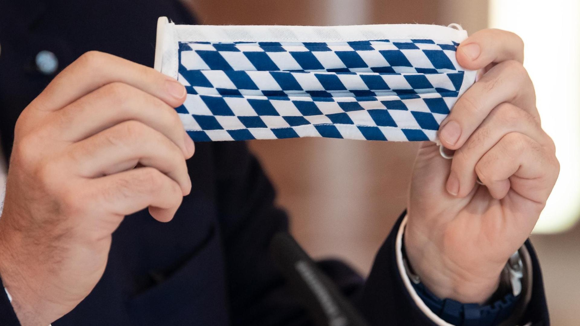 Markus Söder (CSU), Ministerpräsident von Bayern, nimmt an einer Sitzung des bayerischen Kabinetts teil und hält dabei einen Mundschutz mit der bayerischen Rautenflagge in den Händen.