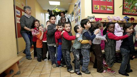 Kinder in einer Kindertagesstätte laufen in einer einer Schlange.