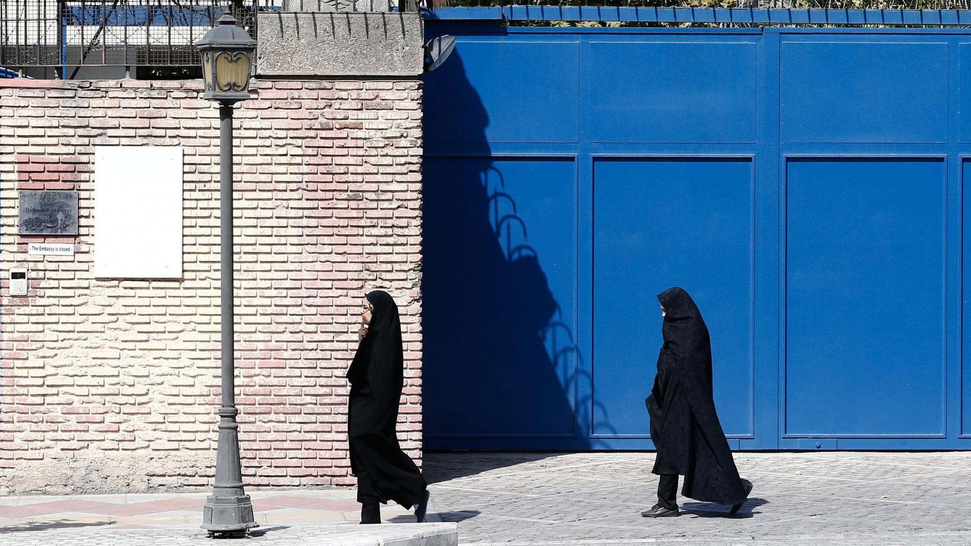 Zwei verschleierte Frauen gehen vor dem Eingang der britischen Botschaft in Teheran einen Weg entlang. Zwei verschleierte Frauen gehen vor dem Eingang der britischen Botschaft in Teheran einen Weg entlang.