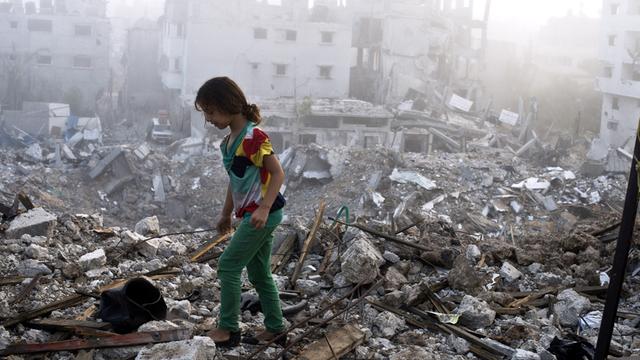 Ein Mädchen läuft über die Trümmer von zerstörten Häusern