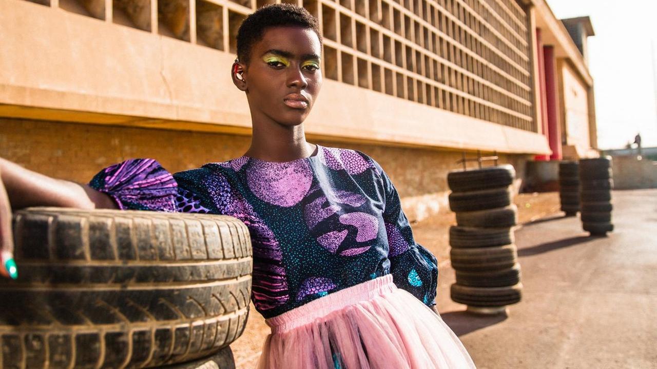 Ein Model im rosa Kleid steht neben Autoreifen, hinter ihr ein Industrie-Gebäude. Ein Model im rosa Kleid steht neben Autoreifen, hinter ihr ein Industrie-Gebäude.