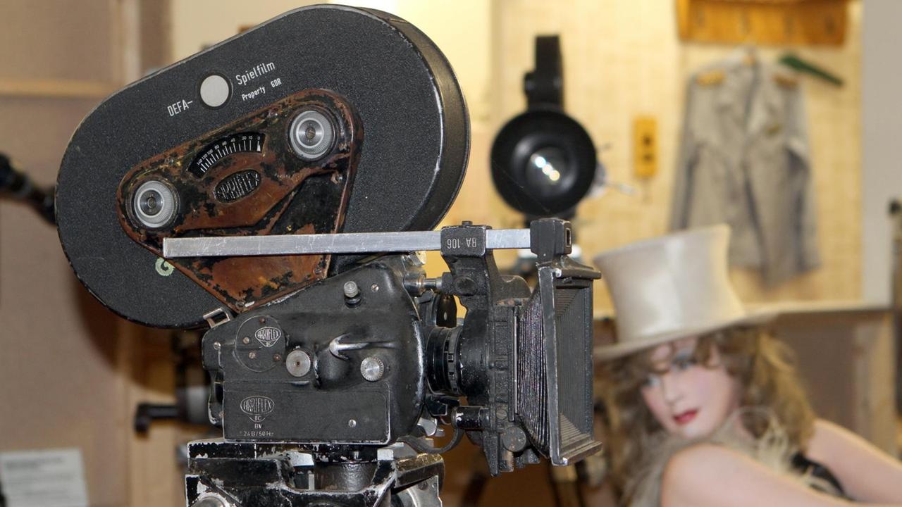 Hinter der Kamera sieht man unscharf eine Puppe, die Marlene Dietrich in ihrer Rolle der Lola in "Der blaue Engel" darstellt, sowie andere Requisiten. Hinter der Kamera sieht man unscharf eine Puppe, die Marlene Dietrich in ihrer Rolle der Lola in "Der blaue Engel" darstellt, sowie andere Requisiten.
