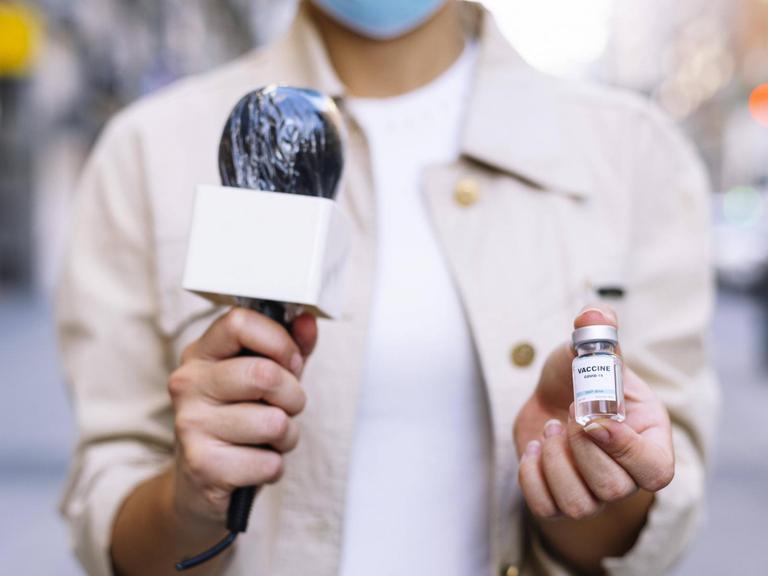 Eine Reporterin hält eine Impfdosis in die Kamera