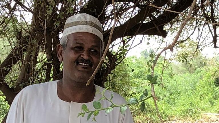 Landwirt Magdy Omar Ali aus dem Sudan neben seiner Kuh