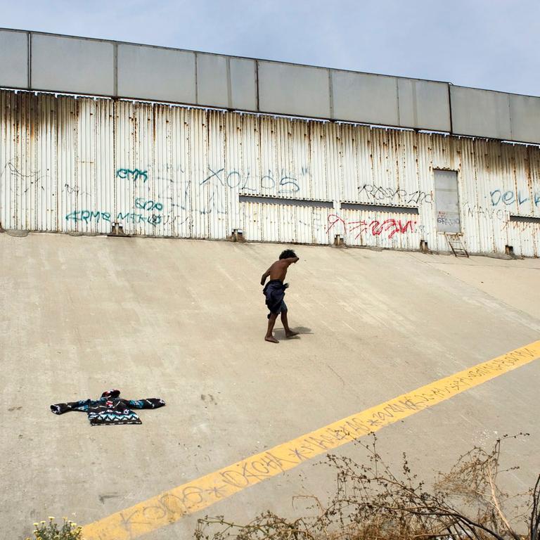 Ein obdachloser Migrant vor der US-Mexikanischen Grenze in Tijuana, Mexiko. Ein obdachloser Migrant vor der US-Mexikanischen Grenze in Tijuana, Mexiko.