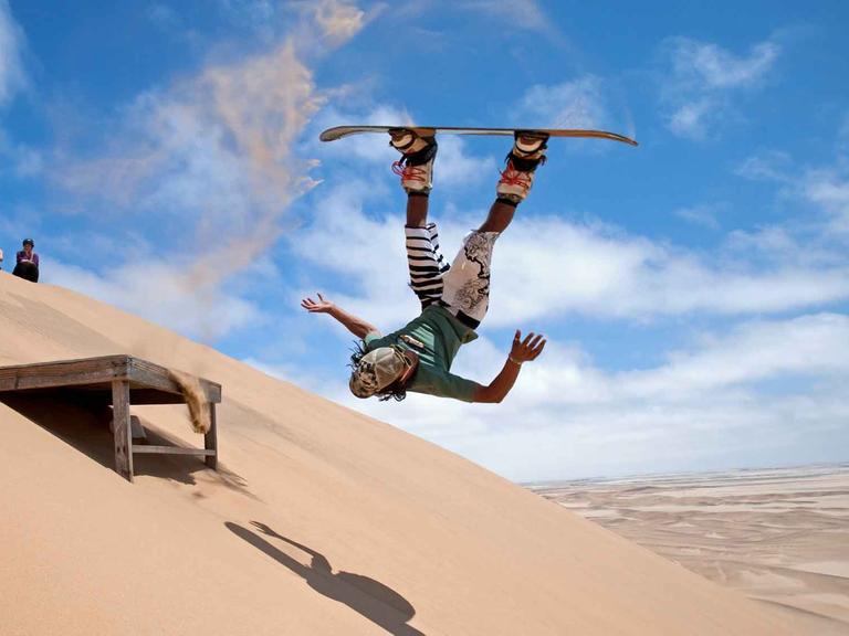 Sandboarder in den Sanddünen der Namib Wüste.