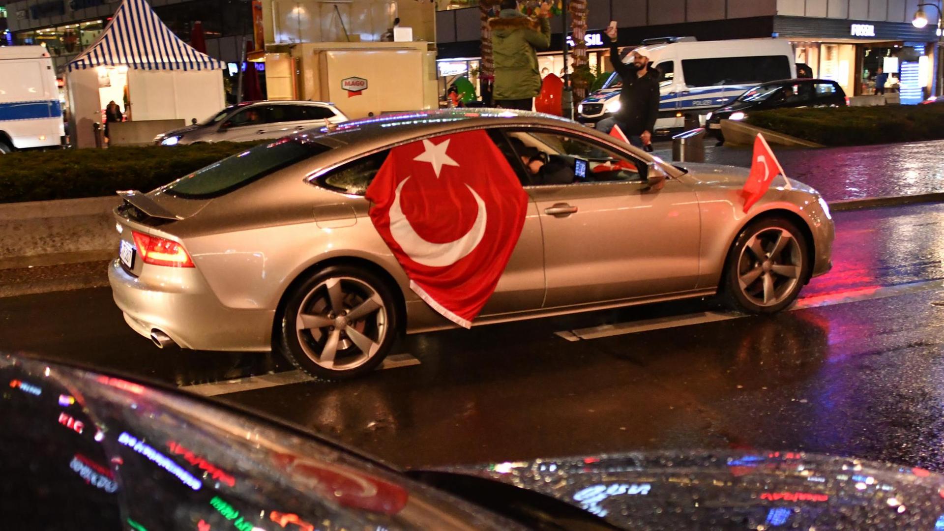 Sie sehen ein silbernes Auto mit einer Türkeifahne in Berlin. Es ist Nacht. Sie sehen ein silbernes Auto mit einer Türkeifahne in Berlin. Es ist Nacht.