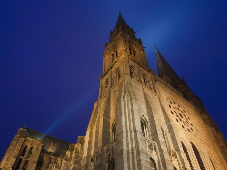 Die Kathedrale von Chartres in der Normandie in Frankreich – von Scheinwerfern bestrahlt, dahinter der Nachthimmel