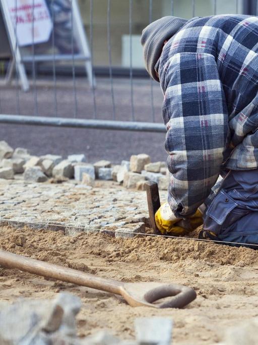 Bauarbeiter beim Verlegen von Kleinsteinpflaster in Berlin.