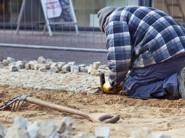 Bauarbeiter beim Verlegen von Kleinsteinpflaster in Berlin.