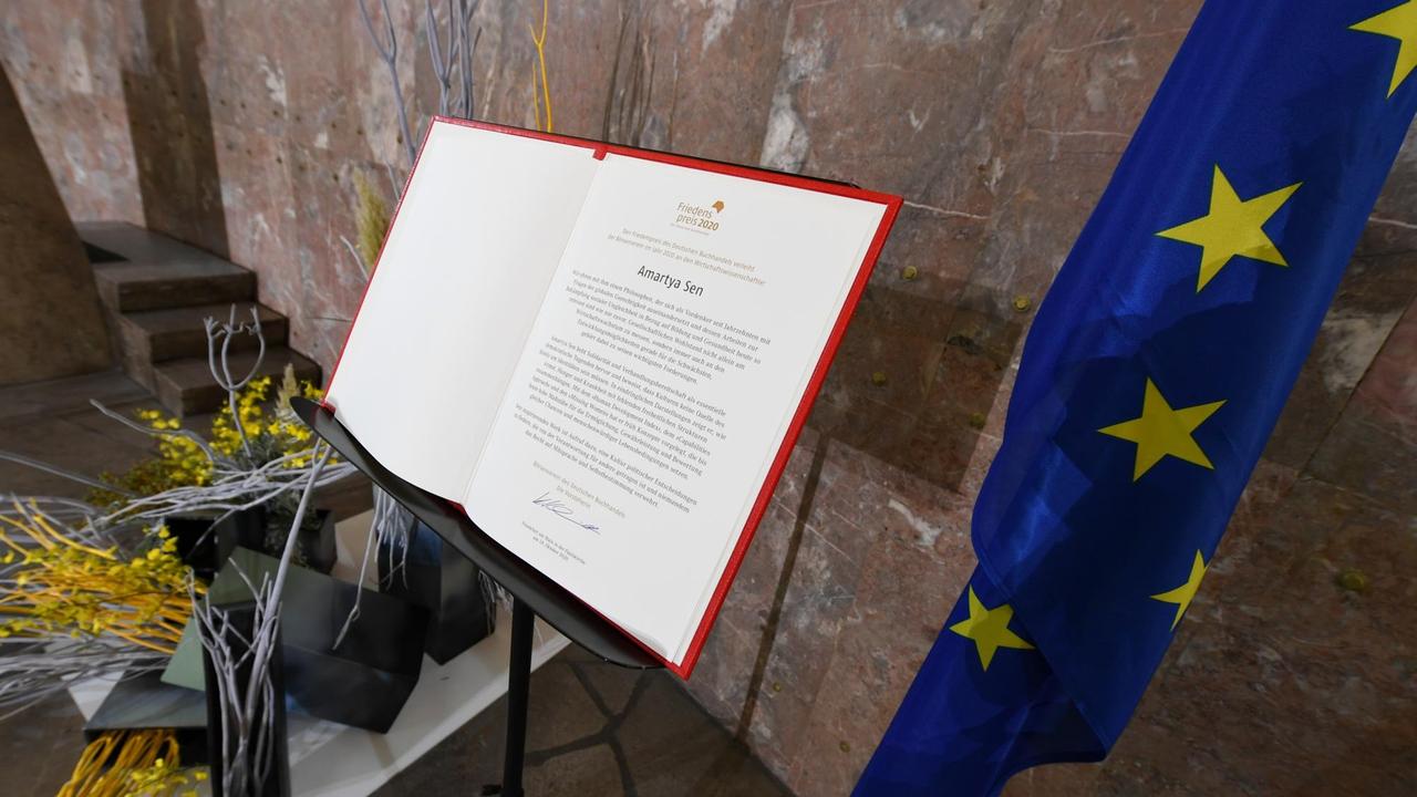 Die Urkunde für Amartya Sen, indischer Wirtschaftswissenschaftler, Philosoph und Nobelpreisträger, liegt in der Frankfurter Paulskirche vor der Verleihung des Friedenspreis des Deutschen Buchhandels aufgeschlagen auf einem Stehpult.
Die Urkunde für Amartya Sen, indischer Wirtschaftswissenschaftler, Philosoph und Nobelpreisträger, liegt in der Frankfurter Paulskirche vor der Verleihung des Friedenspreis des Deutschen Buchhandels aufgeschlagen auf einem Stehpult.