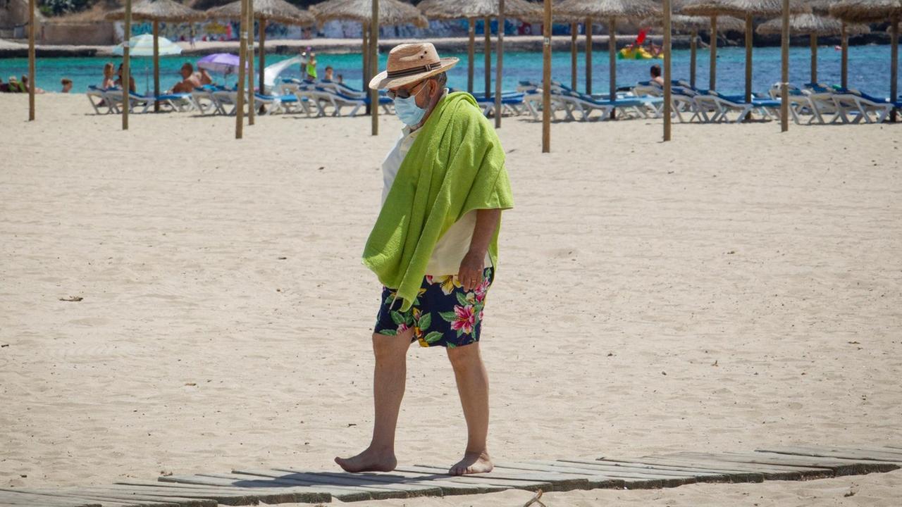 Mann mit Mund-Nasen-Bedeckung am Strand auf Mallorca. Mann mit Mund-Nasen-Bedeckung am Strand auf Mallorca.