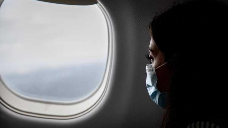 Passagierin im Flugzeug mit Mund-Nase-Bedeckung