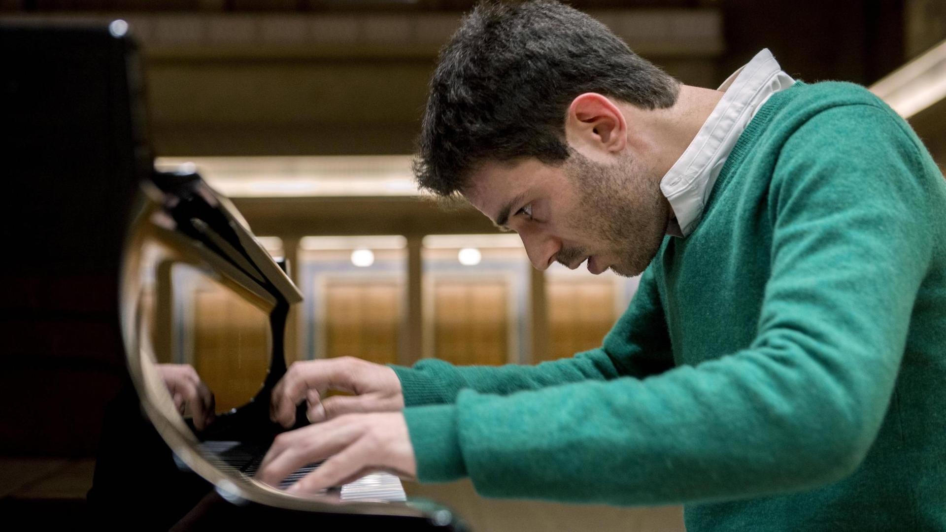 Ein Mann spielt auf einem Flügel, die Hände sind auf den Tasten, er beugt den Oberkörper zum Instrument hin. Ein Mann spielt auf einem Flügel, die Hände sind auf den Tasten, er beugt den Oberkörper zum Instrument hin.