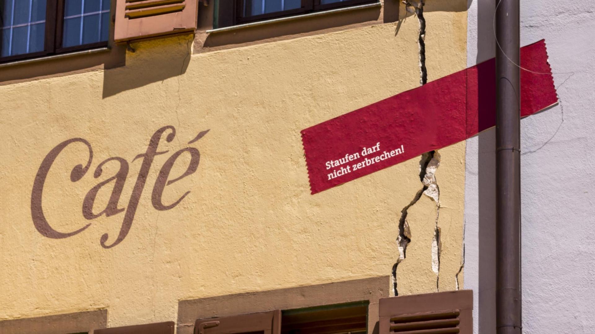 Detail einer Fassade mit Riss. Ein Pflaster über den Riss trägt die Aufschrift „Staufen darf nicht zerbrechen!“ Detail einer Fassade mit Riss. Ein Pflaster über den Riss trägt die Aufschrift „Staufen darf nicht zerbrechen!“