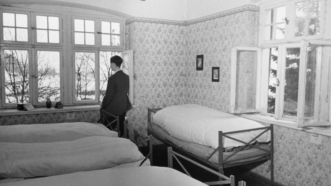 Ein junger Mann schaut im Gemeinschaftsschlafraum aus dem Fenster. Ein junger Mann schaut im Gemeinschaftsschlafraum aus dem Fenster.