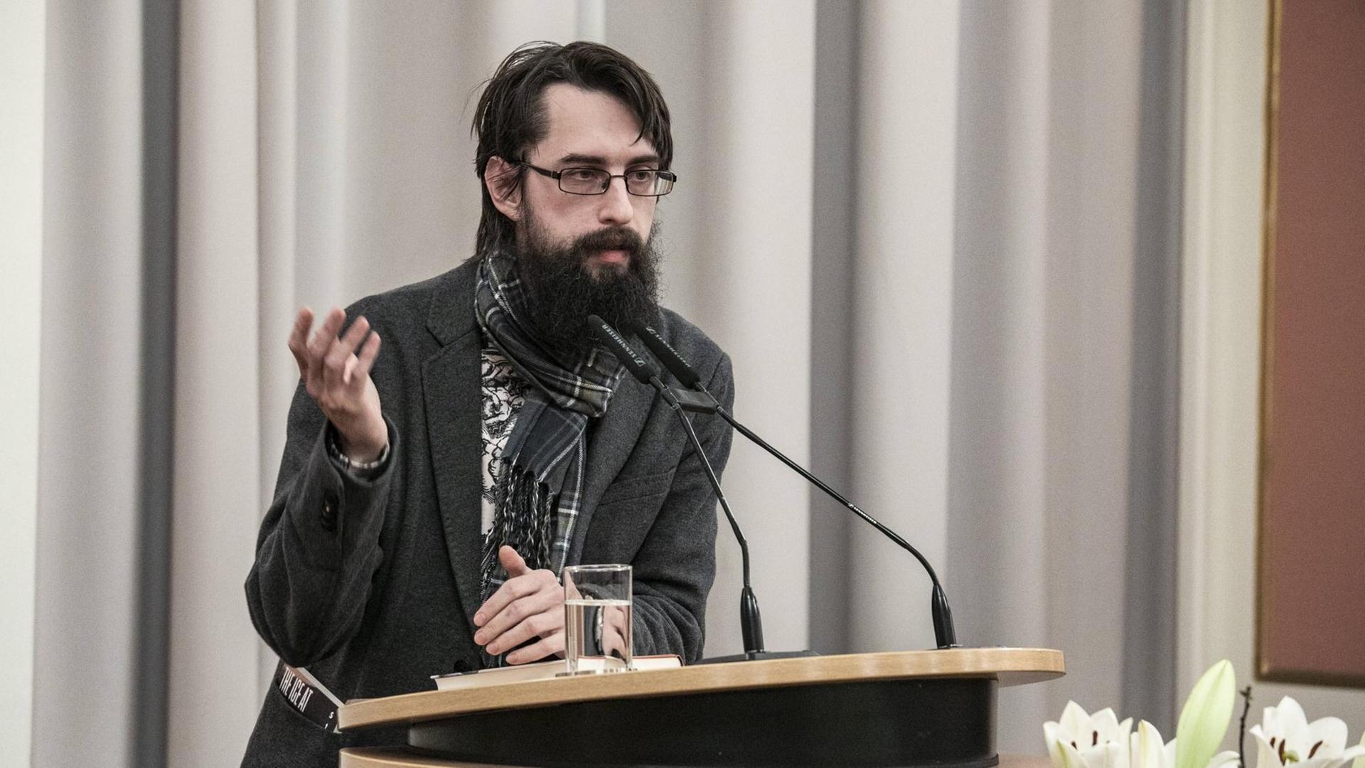 Der Schriftsteller Clemens J. Setz steht an einem Pult und hält eine Rede. Der Schriftsteller Clemens J. Setz steht an einem Pult und hält eine Rede.