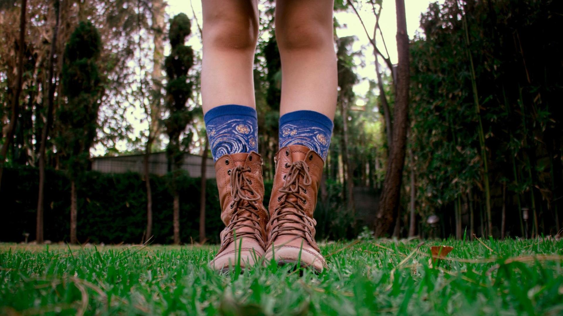 Beine mit blauen bedruckten Socken in braunen Lederstiefeln Beine mit blauen bedruckten Socken in braunen Lederstiefeln