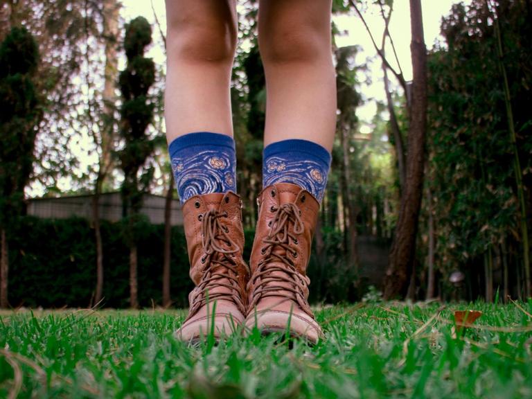 Beine mit blauen bedruckten Socken in braunen Lederstiefeln