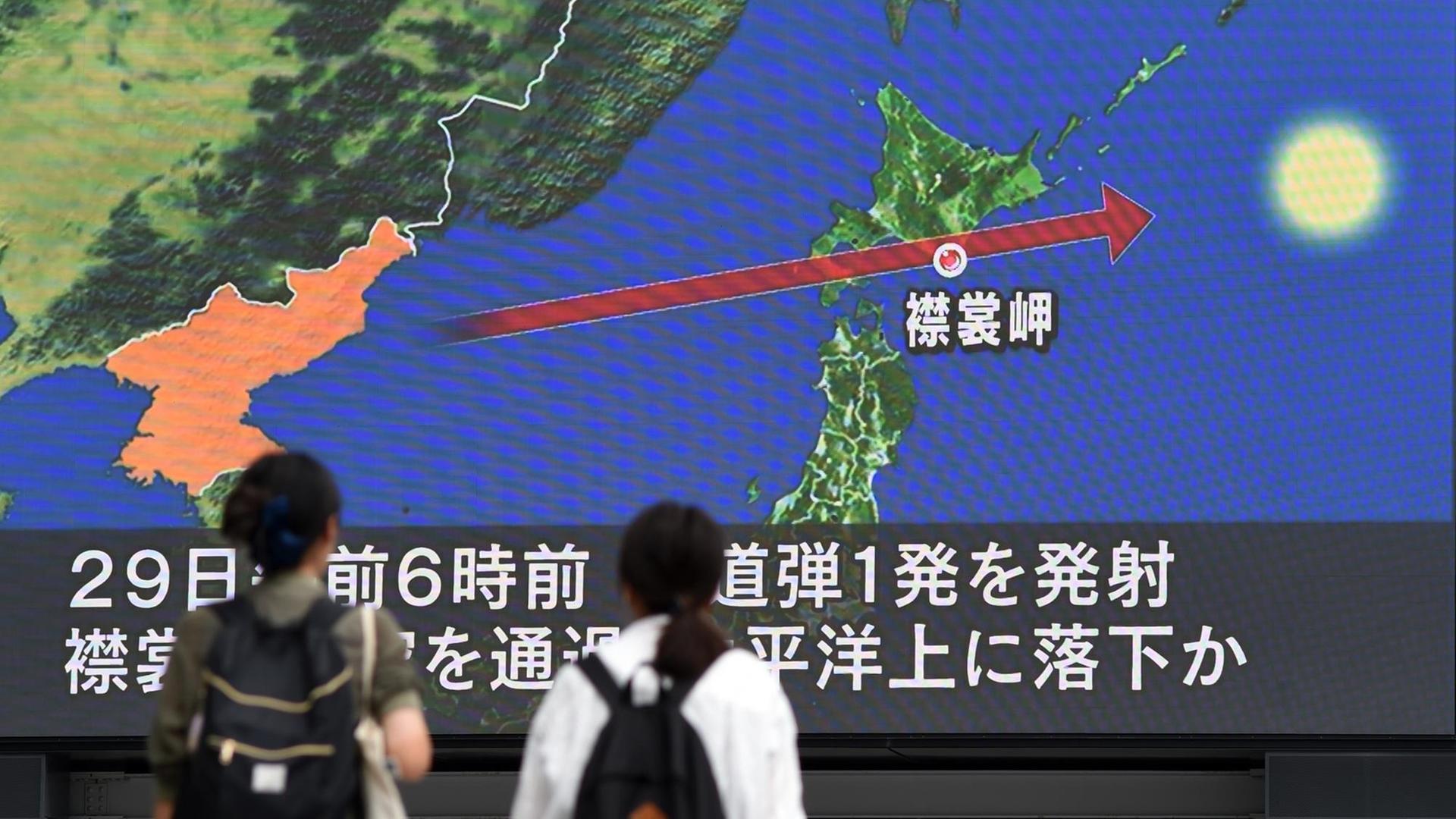 Zwei Personen in Japan verfolgen die Berichterstattung über den nordkoreanischen Raketen auf einem Monitor.